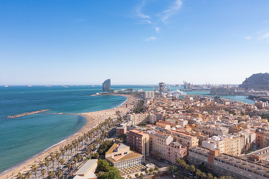Aerial_view_of_Barceloneta_Beach_and_Port_Vell_in_Barcelona 🏙️ Onde ficar em Barcelona, Espanha: os melhores bairros e hotéis para sua viagem